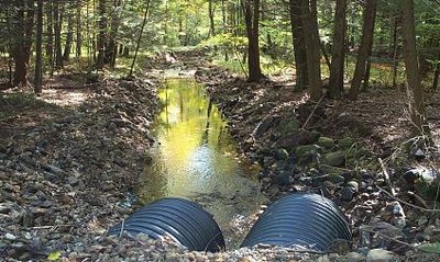 Photo illustrating skewed alignment of culvert outlet that directs high stream flow regimes into the streambank.