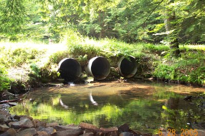 Photo showing the outlet for one of the culverts to be replaced in Bobbs Creek, Pennsylvania.  Note the elevation between the culvert ends and the water level and the concentration of flow through only one of the three culverts.