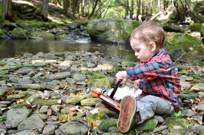 Photo of a very young child with a measuring tape reel on the bank of a trout stream in Northern Pennsylvania.